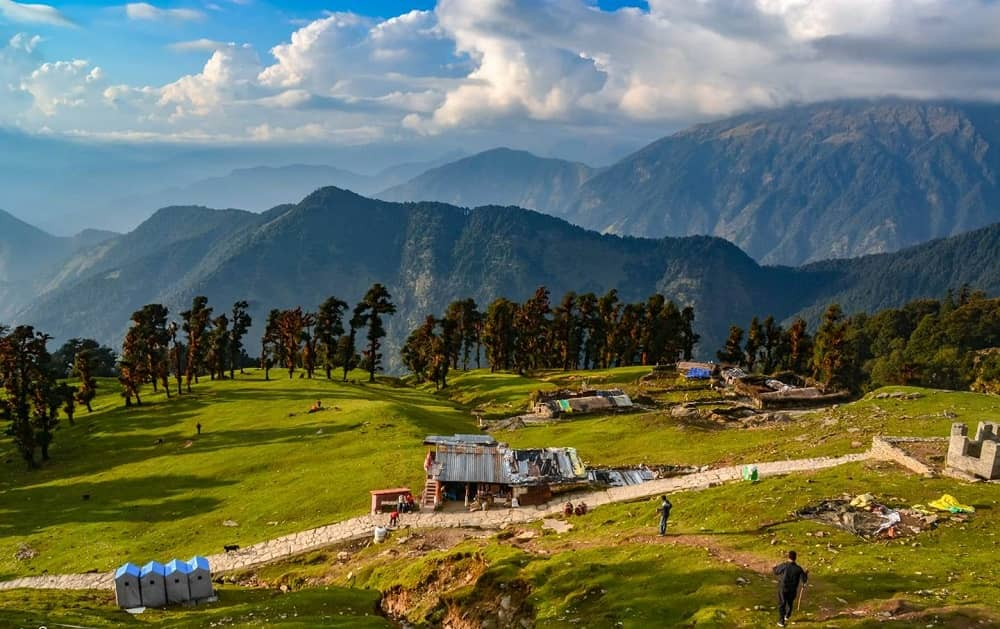 10 Hidden Gems in India Every Traveler Must Visit once Scenic alpine meadows of Chopta, Uttarakhand with lush green hills, scattered huts, and Himalayan mountains in the background