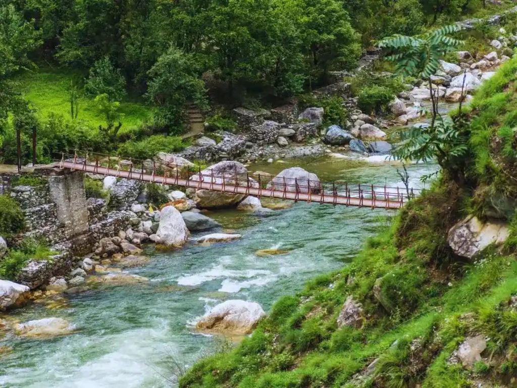 10 Hidden Gems in India Every Traveler Must Visit once Wooden bridge over a flowing river in Tirthan Valley, Himachal Pradesh, one of the best places to visit in India