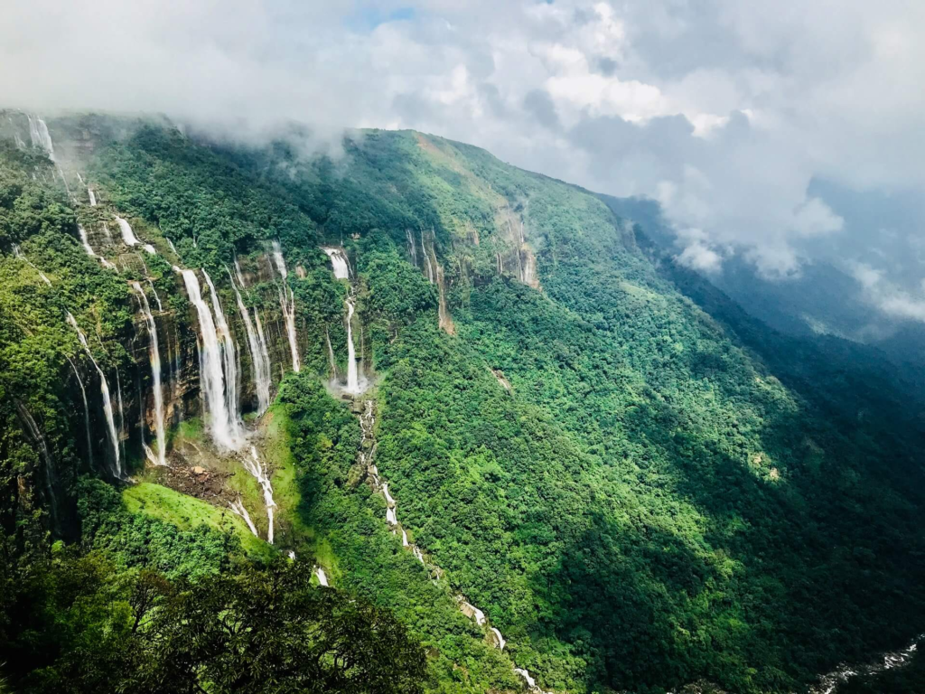 Scenic view of cascading waterfalls and lush green hills in Shillong, highlighting one of the most breathtaking places to visit in Meghalaya.
